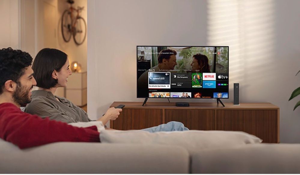Frau sitzt auf Sofa und schaut TV
