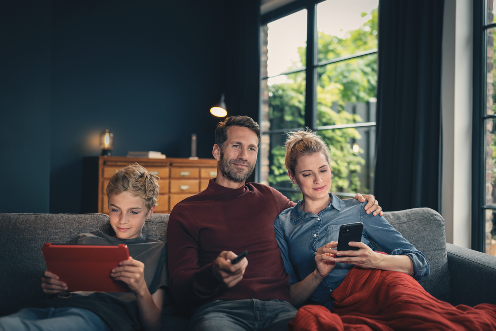Junge-Mann-Frau_auf_Couch_mit_mobilen_Geräten.png