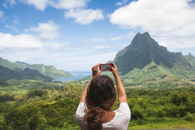 Frau fotorafiert mit Handy Landschaft .jpg KI-generiertes Bild