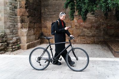 Frau mit Handy in der Hand schiebt Fahrrad .jpg