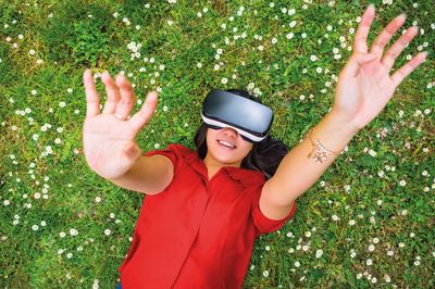 Frau mit VR Brille liegt auf Blumenwiese.jpg KI-generiertes Bild